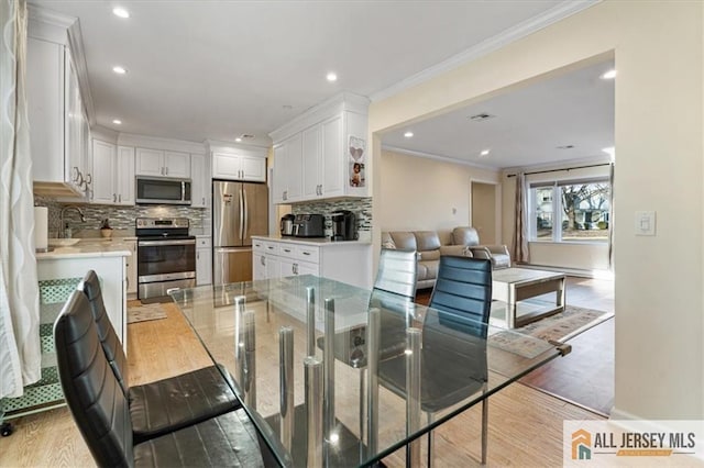 dining room featuring light wood-style flooring, crown molding, and recessed lighting