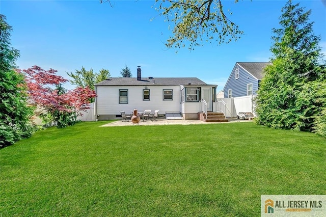 rear view of house with a yard, fence, a chimney, and a patio area