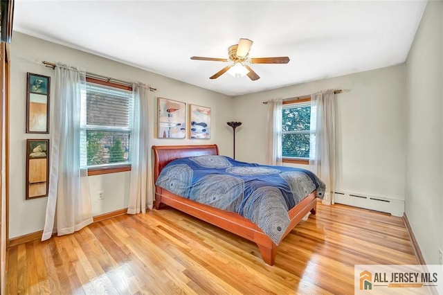 bedroom featuring baseboards, a ceiling fan, light wood-style flooring, and a baseboard heating unit