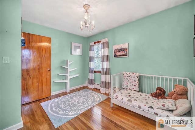 bedroom featuring baseboards, a notable chandelier, and wood finished floors