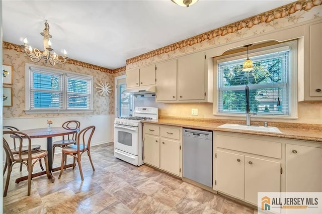 kitchen with white gas range, wallpapered walls, a sink, dishwasher, and a notable chandelier