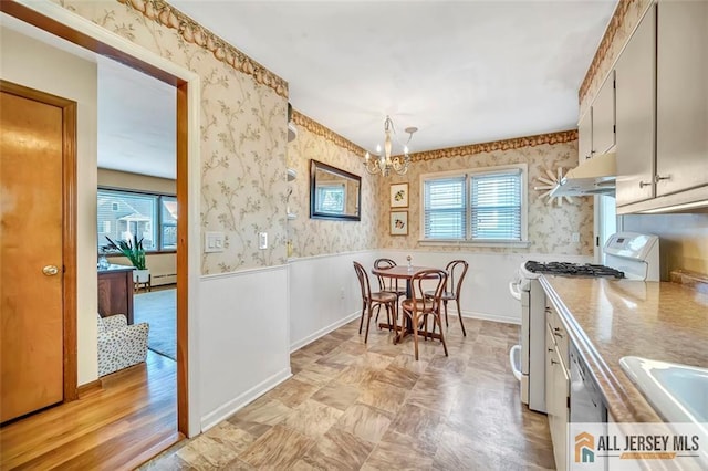 kitchen with an inviting chandelier, a wealth of natural light, white gas range, and wallpapered walls
