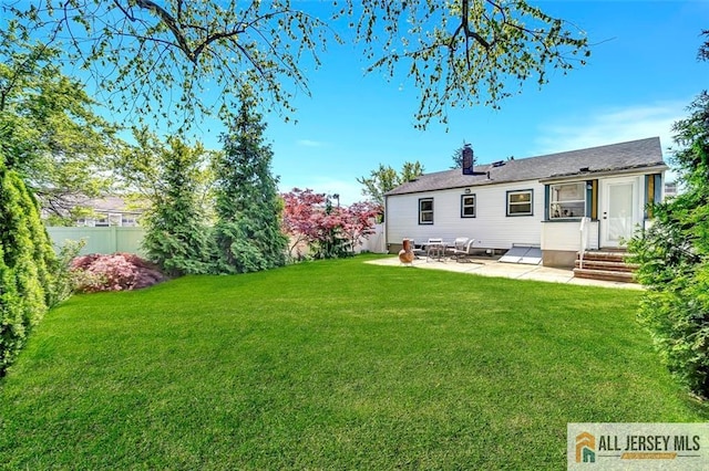 rear view of house with a chimney, a lawn, fence, a patio, and entry steps