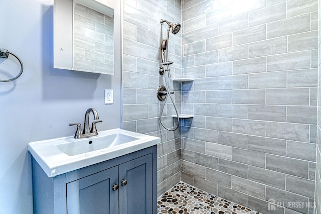 bathroom with vanity and a tile shower