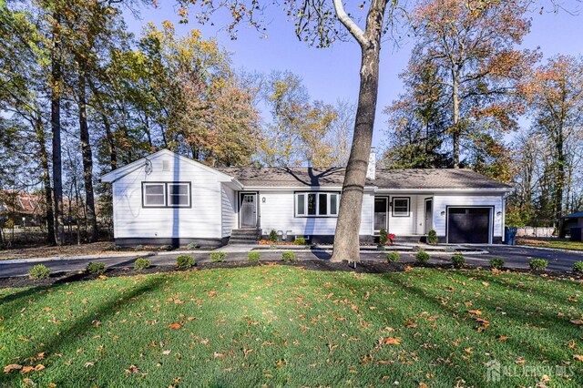 ranch-style house featuring a garage and a front lawn