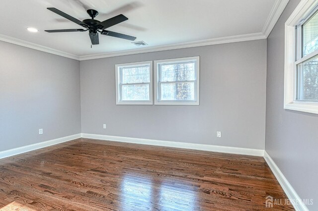 empty room featuring a wealth of natural light, dark hardwood / wood-style flooring, ceiling fan, and crown molding