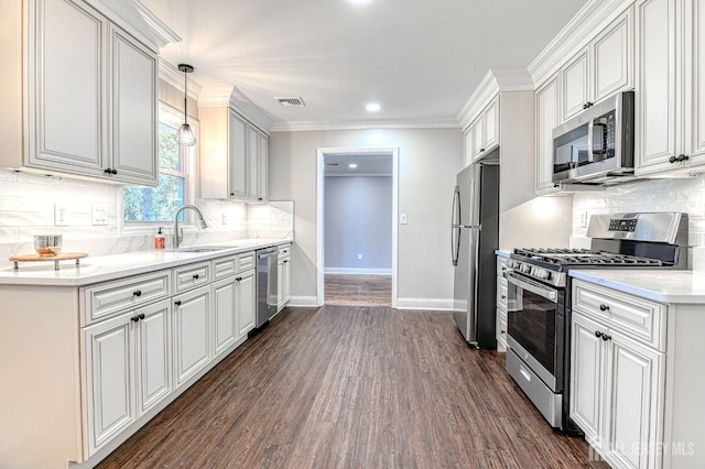 kitchen with sink, hanging light fixtures, dark hardwood / wood-style flooring, decorative backsplash, and appliances with stainless steel finishes