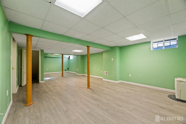 basement featuring a paneled ceiling and light wood-type flooring