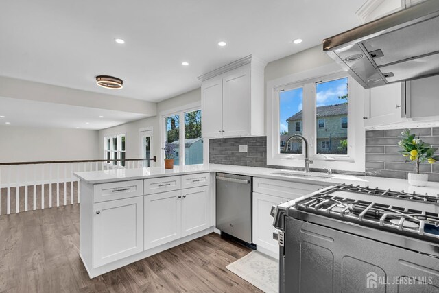 18 Heritage Dr, Edison, NJ 08820 - kitchen featuring dishwasher, black range with gas stovetop, ventilation hood, a peninsula, and light countertops