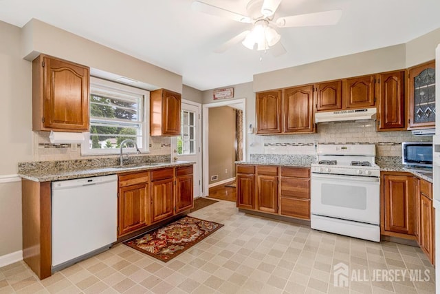 1010 Dorn Ave, Middlesex, NJ 08846 - kitchen featuring white appliances, under cabinet range hood, a sink, brown cabinets, and tasteful backsplash