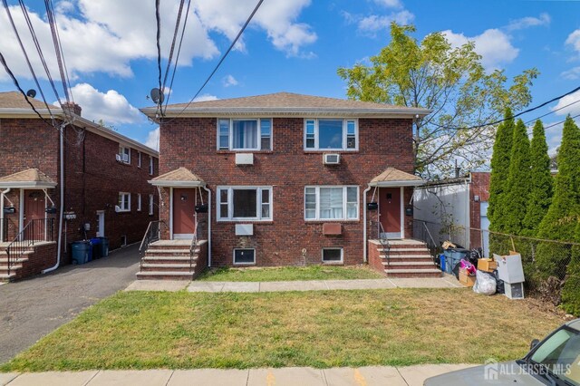 view of front of property with an AC wall unit and a front lawn