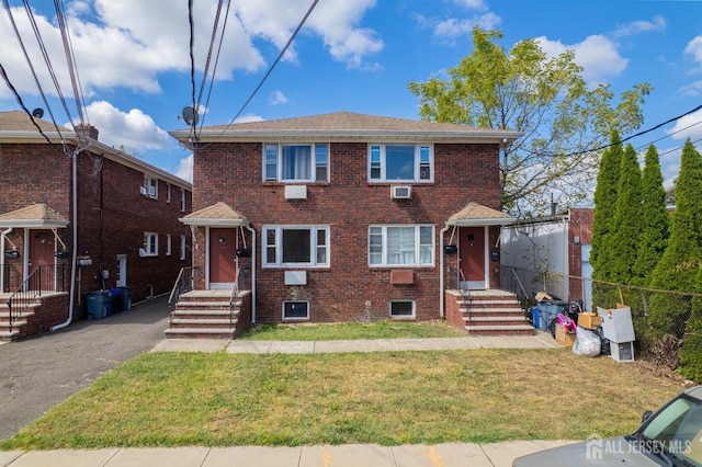 view of front facade with a front lawn and a wall mounted AC