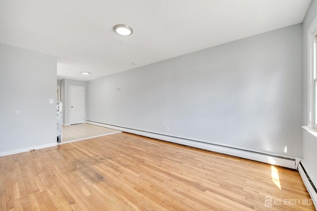 unfurnished room featuring light wood-type flooring and baseboard heating