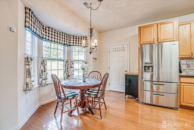 dining area featuring a notable chandelier, light wood-style floors, visible vents, and baseboards