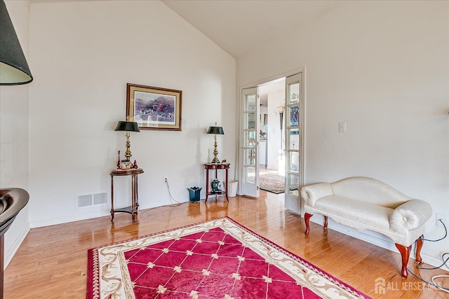 sitting room with visible vents, lofted ceiling, and wood finished floors