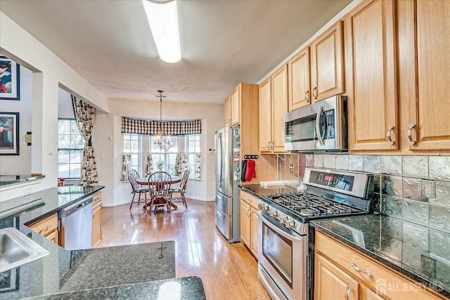 kitchen with light wood-type flooring, light brown cabinetry, stainless steel appliances, an inviting chandelier, and decorative backsplash