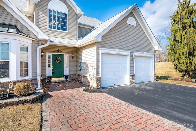 exterior space featuring aphalt driveway, stone siding, a garage, and a shingled roof