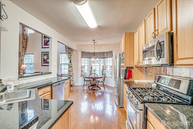 kitchen with light brown cabinets, light wood finished floors, a sink, appliances with stainless steel finishes, and backsplash