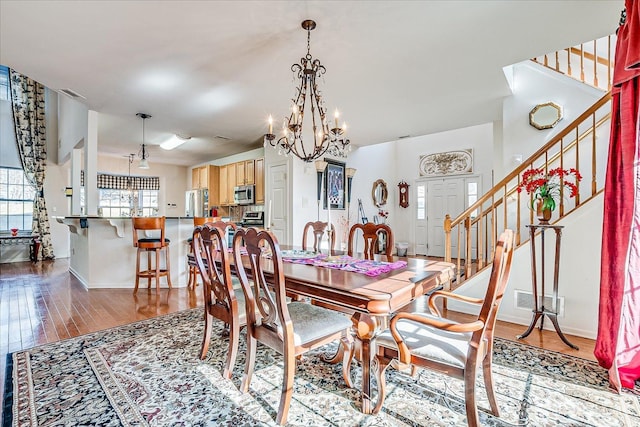 dining area featuring stairway, wood finished floors, baseboards, and a chandelier