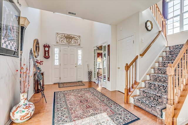 entryway featuring a healthy amount of sunlight, stairs, a high ceiling, and wood finished floors