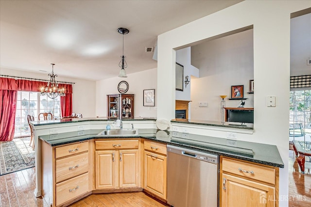 kitchen with stainless steel dishwasher, light wood-style floors, a chandelier, and a sink