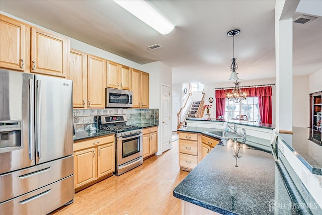 kitchen featuring dark countertops, visible vents, light brown cabinetry, appliances with stainless steel finishes, and a sink