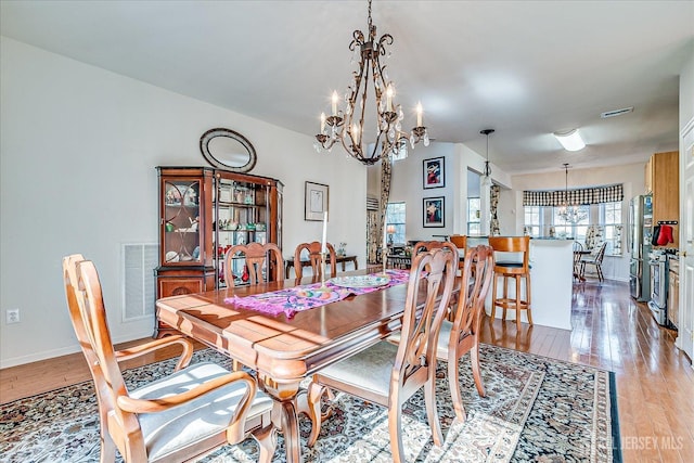 dining area with light wood-style floors, visible vents, and a chandelier