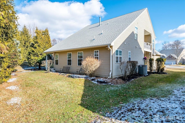 rear view of property with a yard, a shingled roof, and central AC