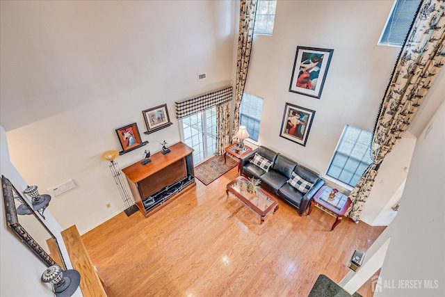 living area featuring visible vents, a high ceiling, and wood finished floors