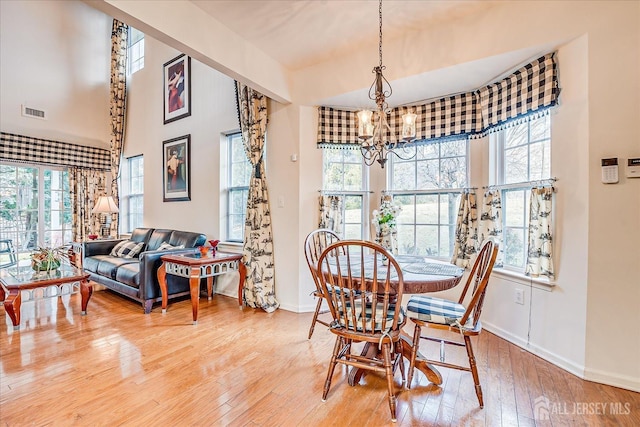 dining space with visible vents, baseboards, an inviting chandelier, and hardwood / wood-style floors