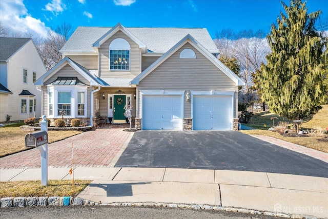 view of front of property with a garage, stone siding, driveway, and metal roof