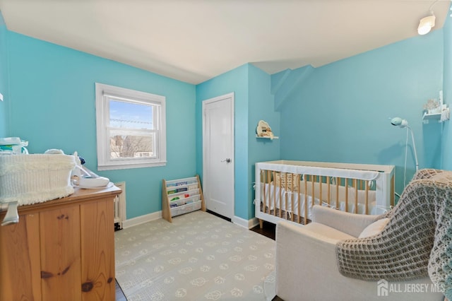 carpeted bedroom with a nursery area, baseboards, and a closet