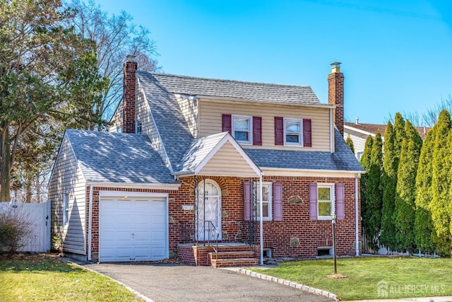 view of front of house with a chimney, an attached garage, driveway, and a front lawn