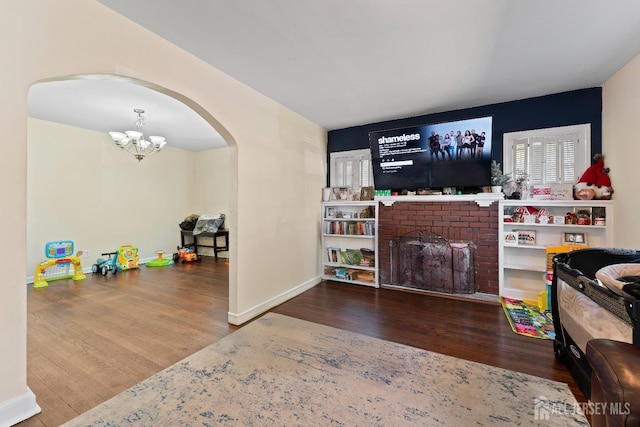 living room featuring a fireplace, wood finished floors, arched walkways, and a chandelier