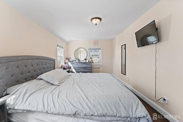 bedroom with radiator heating unit and wood finished floors