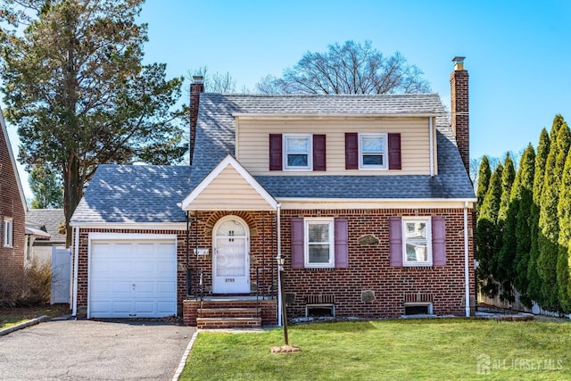 view of front facade with a front lawn, an attached garage, a chimney, and brick siding