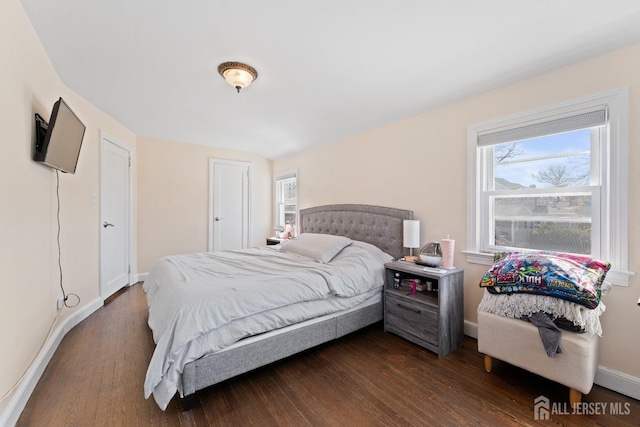 bedroom featuring baseboards, dark wood finished floors, and multiple windows
