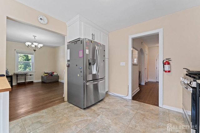 kitchen featuring white cabinets, a chandelier, arched walkways, radiator, and appliances with stainless steel finishes