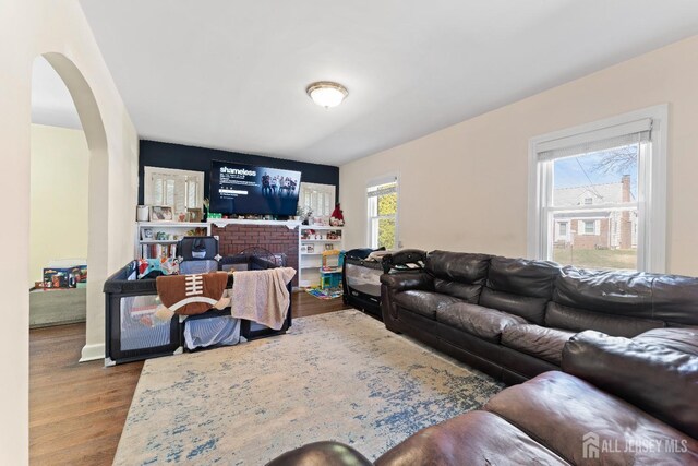 living area featuring arched walkways, wood finished floors, and a fireplace