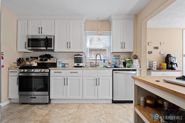 kitchen featuring backsplash, white cabinets, stainless steel appliances, and a sink