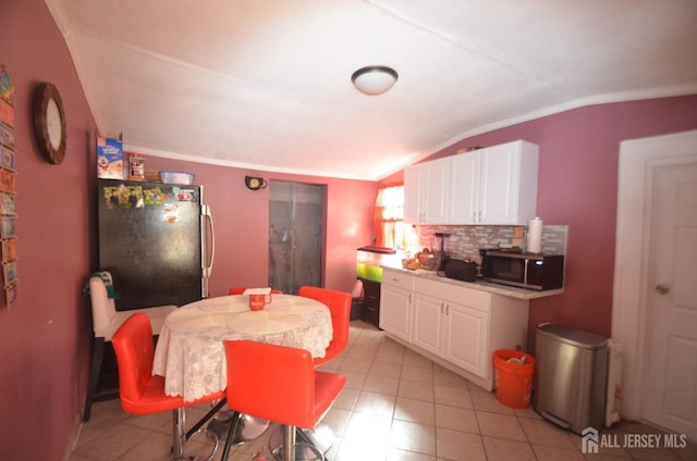 kitchen with light tile patterned floors, appliances with stainless steel finishes, white cabinets, decorative backsplash, and vaulted ceiling