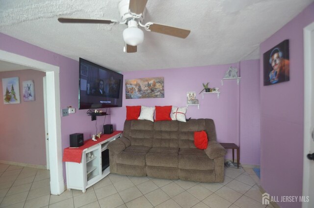 living room featuring light tile patterned floors, a textured ceiling, and ceiling fan