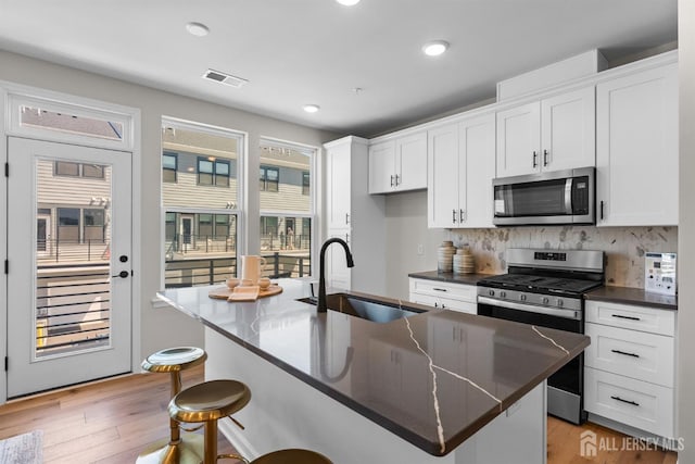 1306 Parker Blvd, West Windsor, NJ 08550 - kitchen featuring appliances with stainless steel finishes, dark countertops, a kitchen breakfast bar, white cabinetry, and recessed lighting
