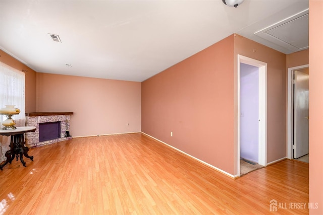 unfurnished living room featuring hardwood / wood-style flooring and a stone fireplace