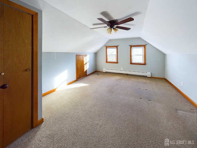 additional living space with ceiling fan, light colored carpet, vaulted ceiling, and a baseboard heating unit