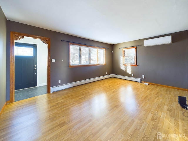 interior space with baseboard heating, light wood-type flooring, and an AC wall unit