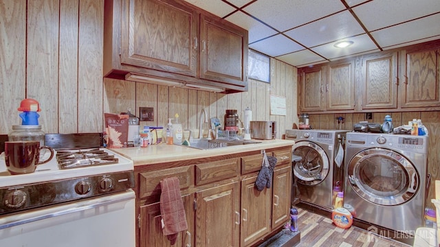 washroom with washer and clothes dryer, wood walls, sink, and light hardwood / wood-style flooring