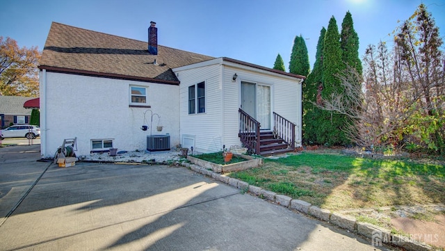 back of house with a lawn and central air condition unit