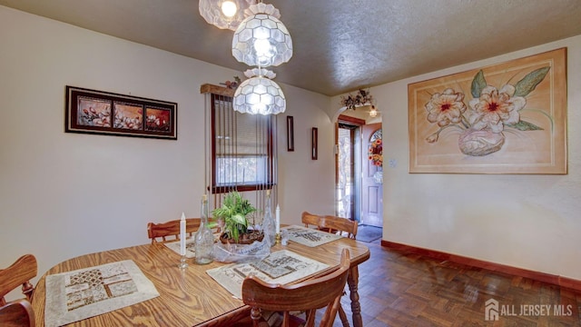 dining space featuring dark parquet flooring and a textured ceiling