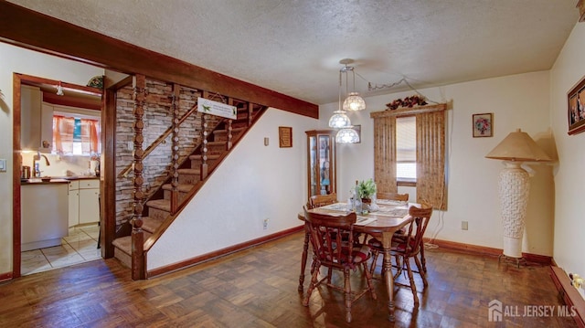 dining space featuring parquet flooring, a textured ceiling, and plenty of natural light